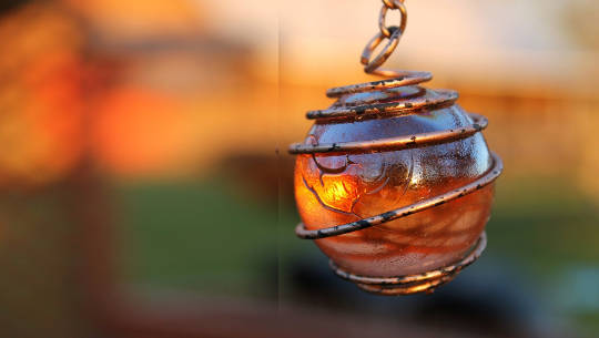 a glowing orb in a pendant with a copper wire wrap