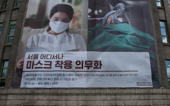 A banner on Seoul’s city hall advocating mandatory mask use. (why batch testing and contact tracing are the two keys to stop the lockdown yo yo)