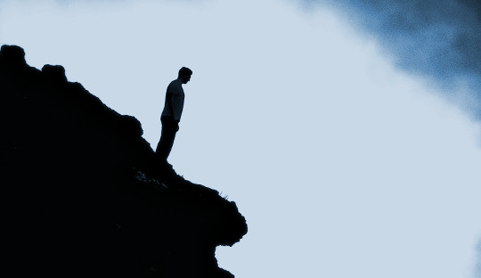man standing alone on the edge of a cliff
