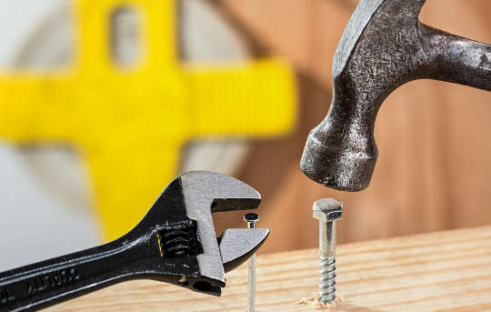 a hammer trying to hammer in a bolt, and a wrench trying to work on a nail