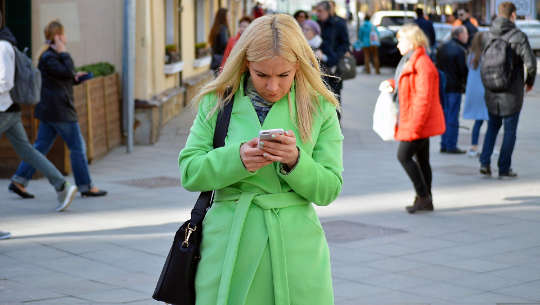 woman on the street looking intently at her phone