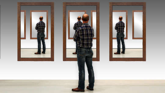 man pausing to look at his reflection in three  separate mirrors