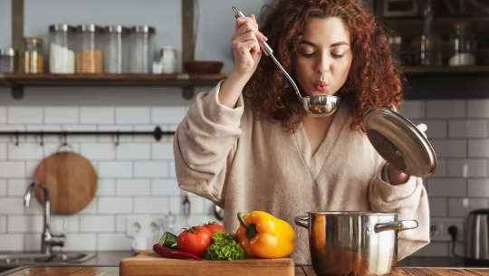 woman tasting food as it is cooking