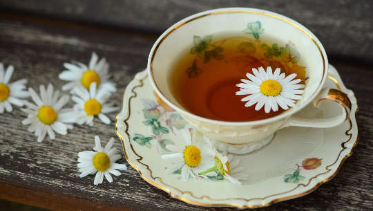 a cup of tea with a flower floating on top in a delicate porcelain cup