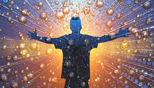 a man with arms outstretched surrounded by atoms on beams of light