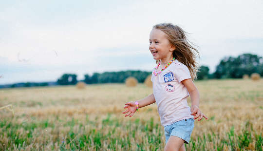 a young girl running joyfully across a field