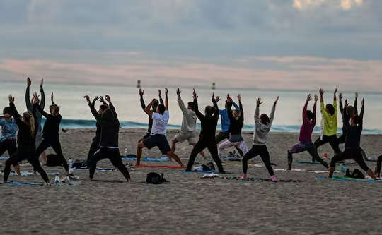 group of people doing yoga on the beach