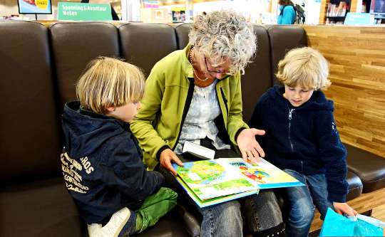 a grandmother reading to her two grandchildren