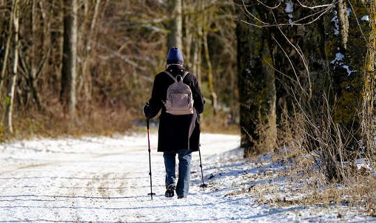 a woman on foot walking on a snowy road