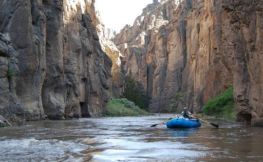 person rafting solo down a canyon river