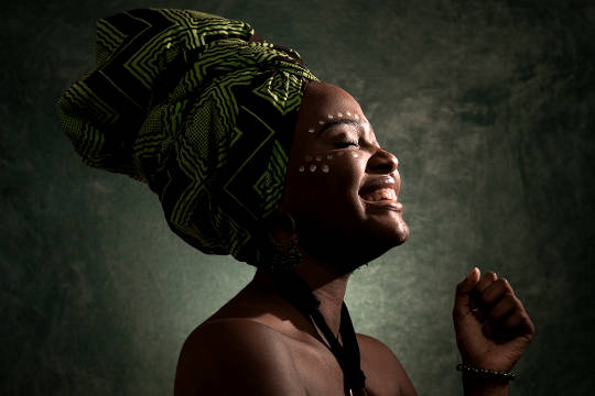 African woman wearing a headress with eyes closed and smile