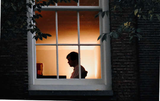 person sitting alone in a house, seen through a window