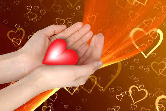 hands holding out a glowing heart with a background of a myriad of hearts