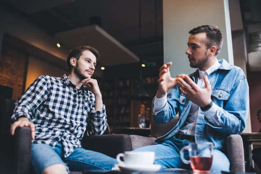 two men in conversation - one speaking, one listening