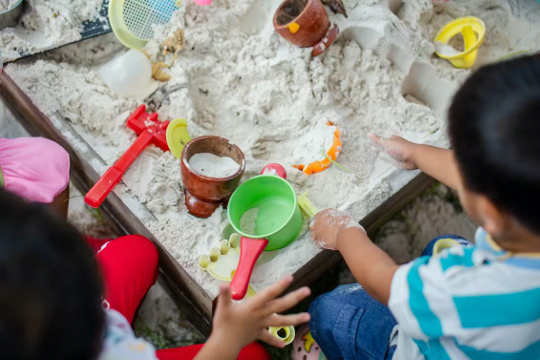 children playing in a sandbox with different cups and tools