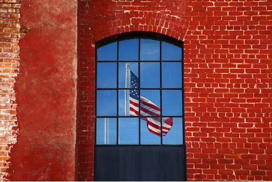a US flag seen through a window in a red brick wall