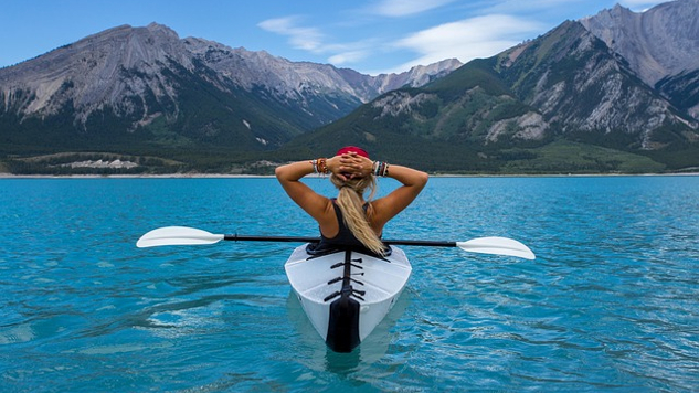 woman sitting and relaxing in a kayak in the middle of a lake