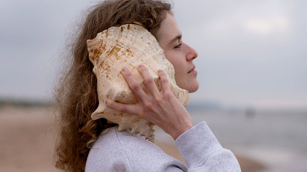 woman listening to a conch shell