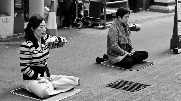 two women meditating on the sidewalk