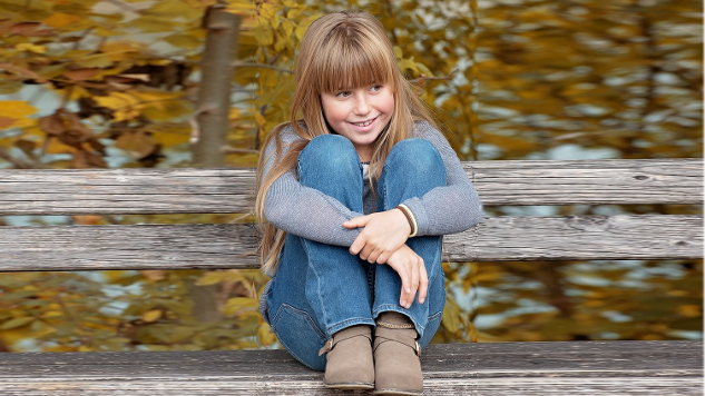 smiling young girl sitting outside on a bench