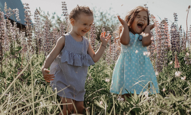 two young children playing joyfully out in Nature