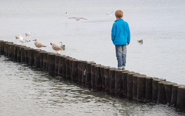 young boy standing on a breakwater