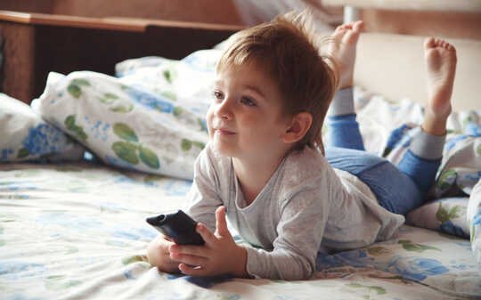 Little boy on bed watching TV