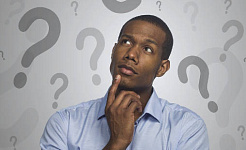 man with a finger on his chin looking up at a backdrop of question marks