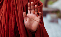 Monk holding up a hand in a mudra gesture