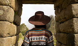 Indian woman standing under a stone arch in Machu Picchu