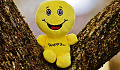 a bright yellow plush toy with a huge smile and the word happy written on its body