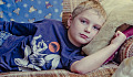 cranky-looking young boy laying on the couch