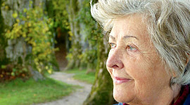 an older woman standing outside looking at something in the distance
