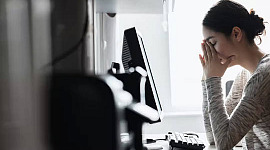 a woman at a computer with her hands covering her face