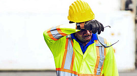 A construction worker wipes his forehead in the heat